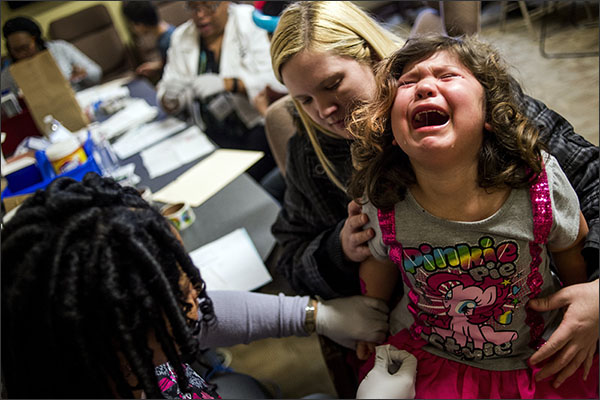 Flint Mich. resident Sarah Truesdail holds her daughter Gabriella Venegas 5 while a health official pricks her finger with a needle for a free lead test