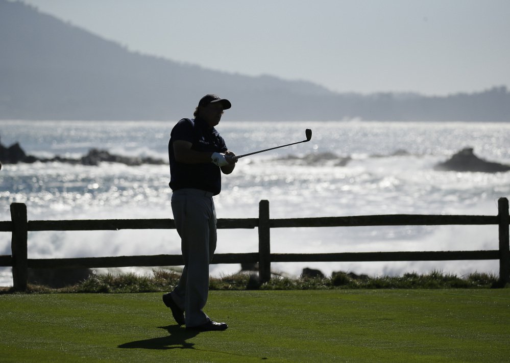 Leader Phil Mickelson is silhouetted as he hits from the 18th tee during the third round of the AT&T Pebble Beach National Pro Am golf tournament Saturday at Pebble Beach California