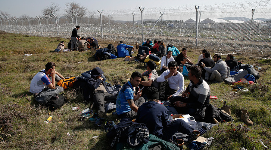 Migrants from Afghanistan who were sent back from the Serbian border rest next to a border fence at the Macedonian Greek border in Gevgelija Macedonia