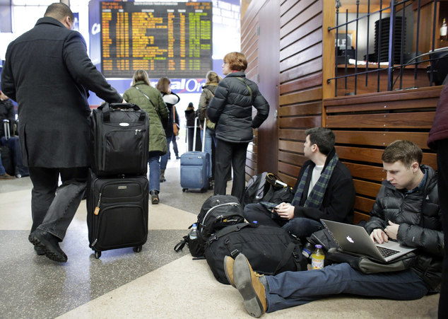 Business travelers James Goldstein right and Dan Shoten second from right wait for their delayed train as other passengers left watch the train departu