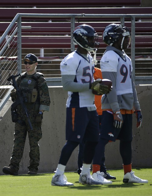 A security officer watches as Denver Broncos players wait for a drill during an NFL football practice in Stanford Calif. Thursday Feb. 4 2016