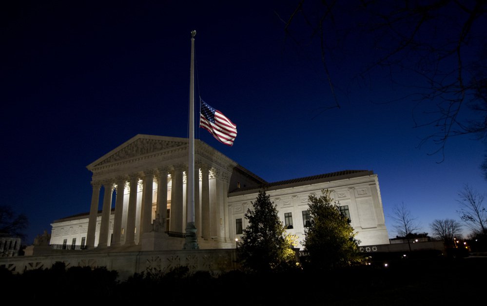 An American flag flies at half-staff in front of the U.S. Supreme Court building in honor of Supreme Court Justice Antonin Scalia as the sun rises in Washington Sunday