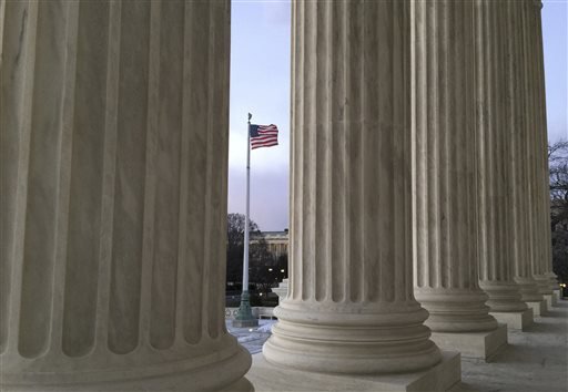 The U.S. flag blows in the wind seen through columns at the Supreme Court building in Washington on Saturday Feb. 13 2016. On Saturday Feb. 13 2016 the U.S. Marshals Service confirmed that Scalia has died at the age of 79