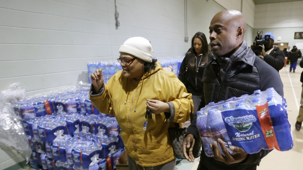 R&B singer Kem helps Mwamini Wallace carry bottled water to her vehicle in Flint Mich. last month