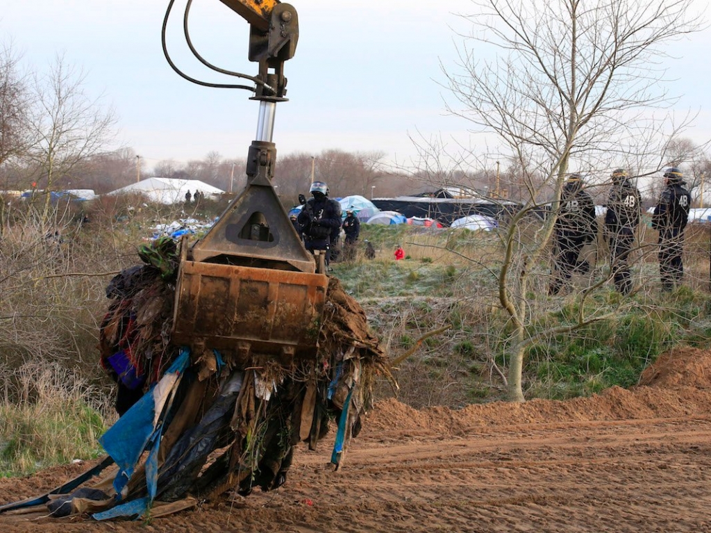 A crane is used to clear dismantled shelters of the camp known as the