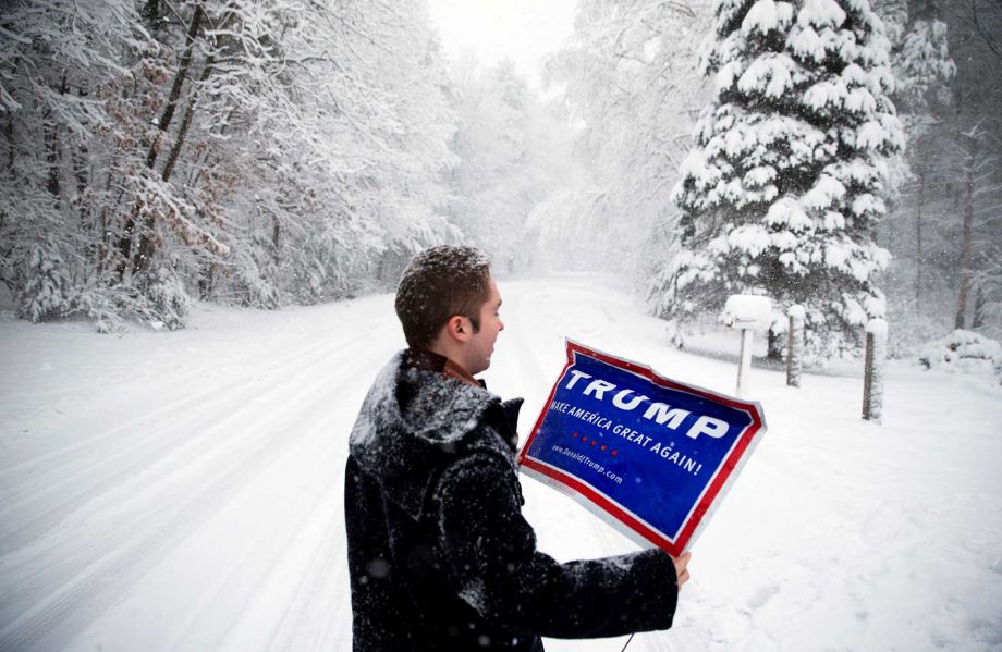 James Radcliffe a volunteer for Republican presidential candidate Donald Trump places a sign outside a home while walking through the snow knocking on doors in search of Trump supporters Friday Feb. 5 2016 in Londonderry N.H. The twenty-two year old