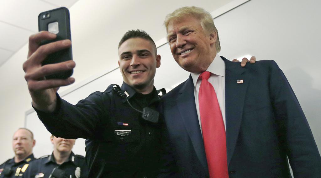 Patrolman James Pittman poses for a selfie with Republican presidential candidate Donald Trump during a campaign stop at police headquarters in Manchester N.H. Thursday Feb. 4 2016