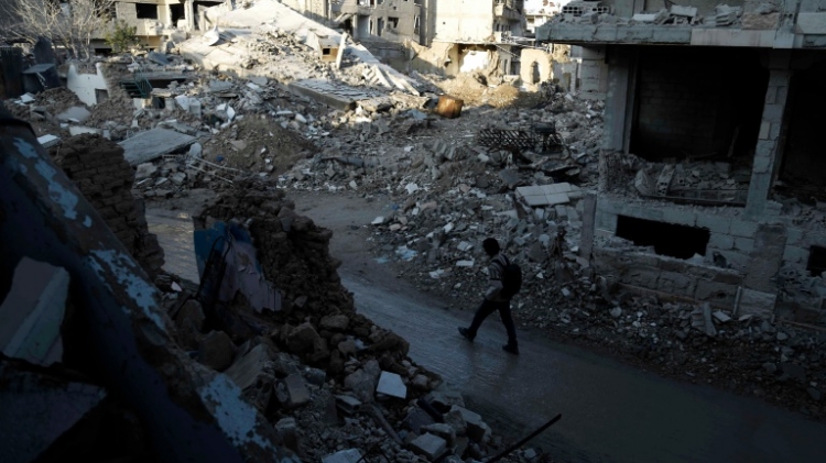 A Syrian man walks along a street damaged by shelling in the neighbourhood of Jobar on the eastern outskirts of the capital Damascus