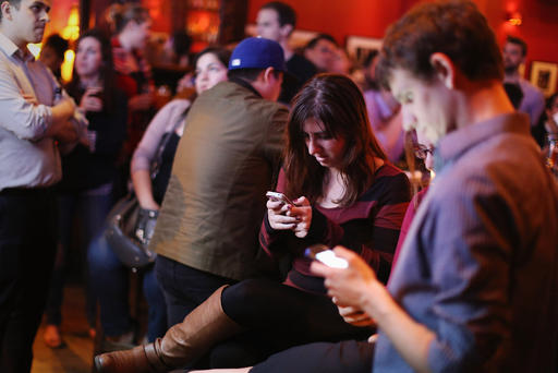 Young adults split their attention between a televised Democratic debate and using their smart phones during a watch party in Washington DC. Oct. 13 2015