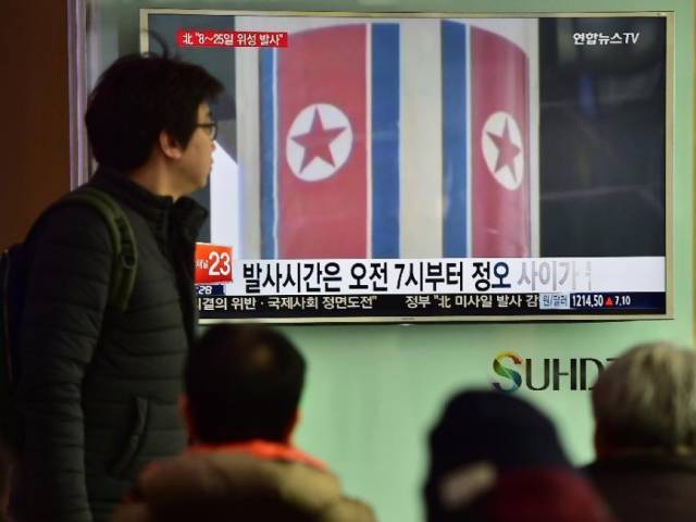 People watch a news report on North Korea's planned rocket launch as file footage from North Korea's 2012 launch of the Unha-3 rocket plays on a TV screen at a railway station in Seoul