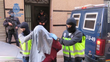 Spanish police wearing balaclavas escort one of the terror suspects arrested Sunday