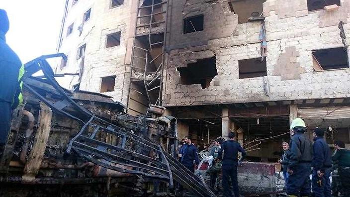 Syrian people and soldiers inspect the site of bombing in the district of al Sayeda Zainab in southern Damascus Syria