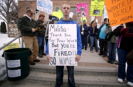 Anti-militia demonstrator Andrew Snyder carries a sign during a protest outside the Harney County Courthouse in Burns Oreg