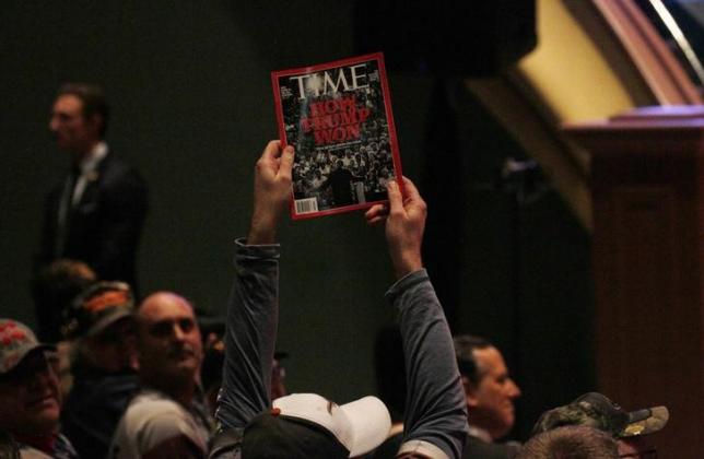 A supporter holds up a copy of Time Magazine during Trump's speech at a veteran's rally in Des Moines Iowa