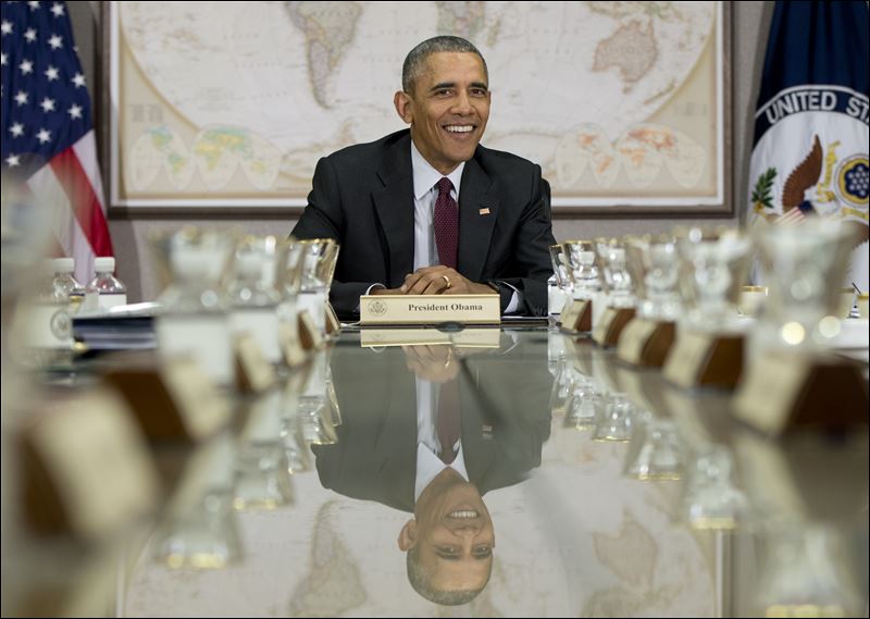 President Barack Obama is reflected in the conference table before a meeting of his National Security Council at the State Department in Washington today