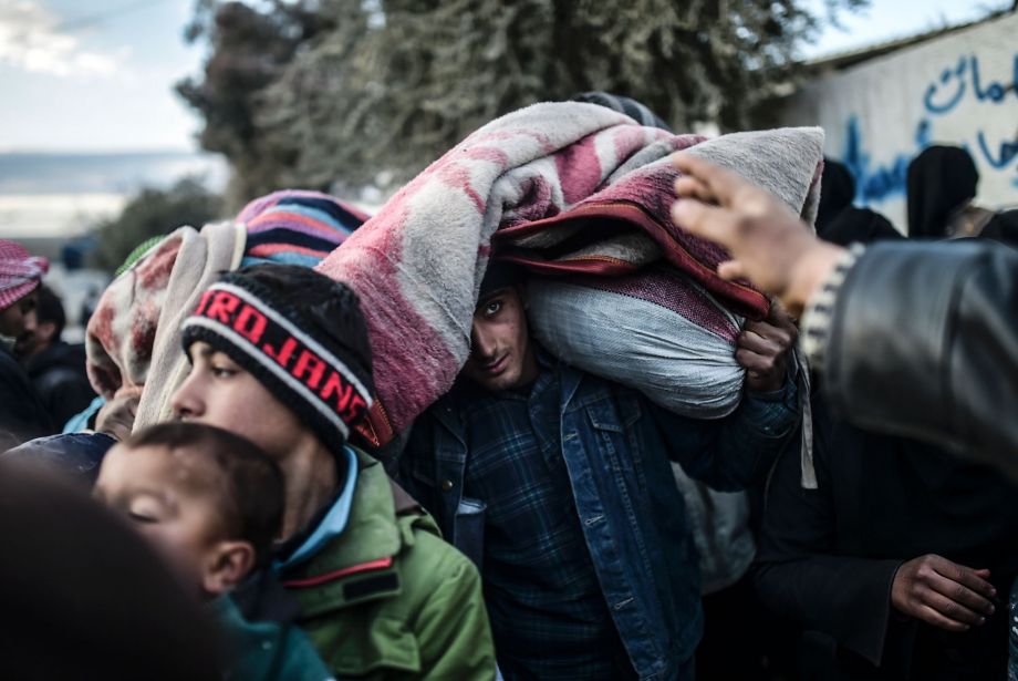 A man carries belongings as Syrians fleeing Aleppo wait near a Turkish crossing gate. Almost 40,000 civilians have fled a government offensive and Turkey is bracing for a wave of refugees