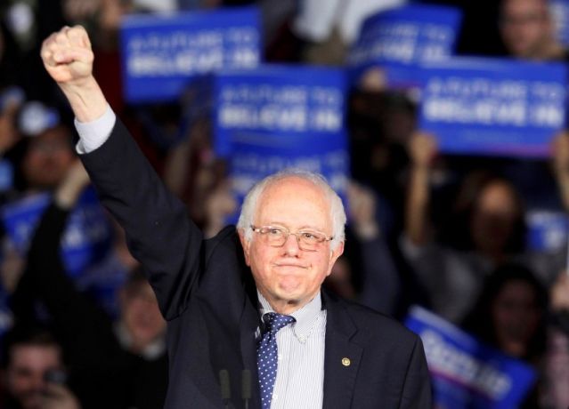 U.S. Democratic presidential candidate Bernie Sanders raises a fist as he speaks at his caucus night rally in Des Moines