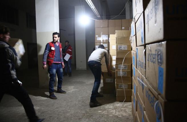 Syrian Red Crescent staff survey the delivery of humanitarian aid in the rebel-held Eastern Ghouta area on the outskirts of Damascus on Feb. 23 2016 during an operation to deliver aid to thousands of besieged Syrians