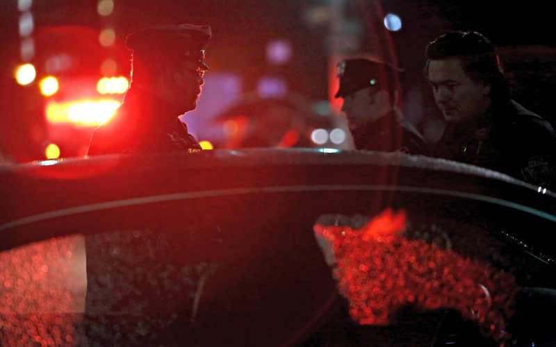 Members of the New York Police department speak to a person in a car near the building where two New York police officers were shot in the Bronx borough of New York