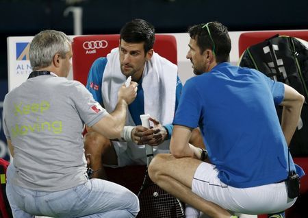 Novak Djokovic of Serbia receives treatment before withdrawing from his match against Feliciano Lopez of Spain at the ATP Dubai Duty Free Tennis Championships