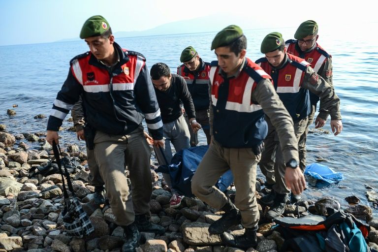 Turkish gendarmes carry the body of a migrant on a beach in Canakkale's Bademli district