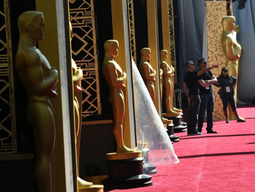 Workers put the finishing touches to the red carpet a day ahead of the 88th Academy Awards