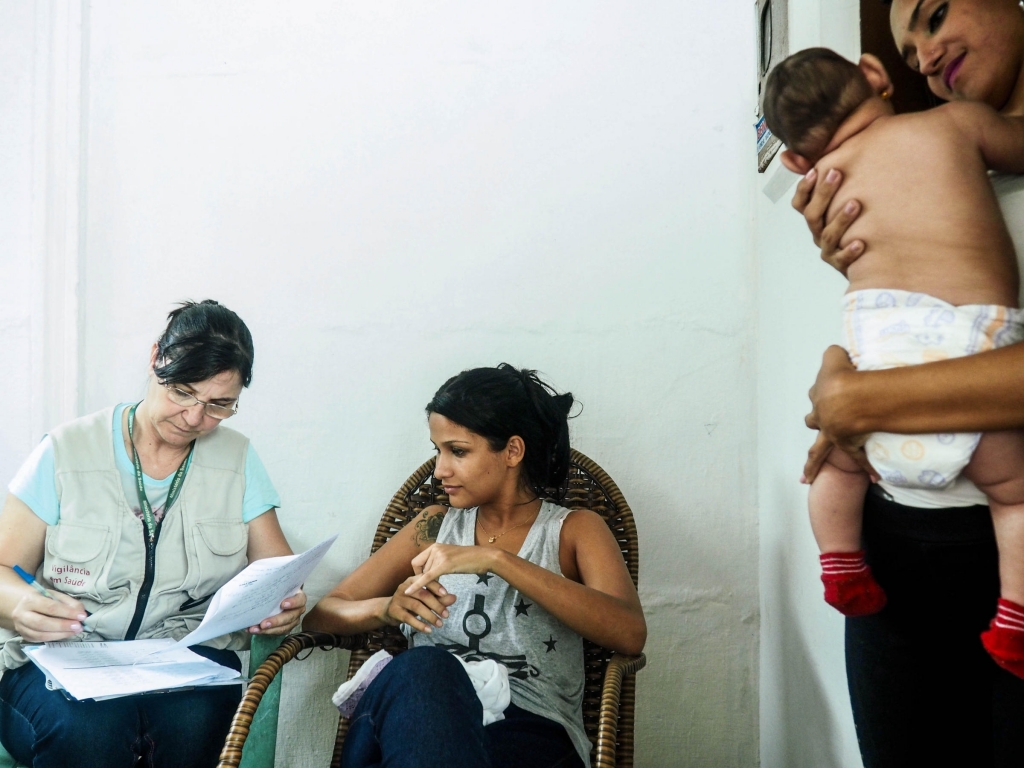 Marcia Andrade an agent from Brazil's Ministry of Health interviews Camila Alves 22. A friend holds Alves&#039 2-month-old daughter