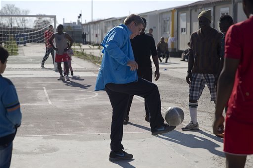 IOC President Thomas Bach plays soccer with refugees during his visit at a refugee camp in Athens on Thursday Jan 28 2016. Bach says the torch relay for this year's Olympics in Rio de Janeiro will include a stop at a refugee camp in Athens. He also