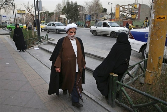 A clergyman make his way in a sidewalk in downtown Tehran Iran Sunday Feb. 28 2016