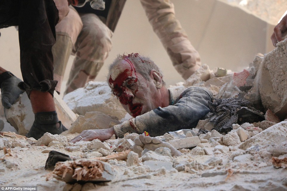 A group of rescuers race to help free him from the concrete and debris after he was seen trying to drag himself to safety