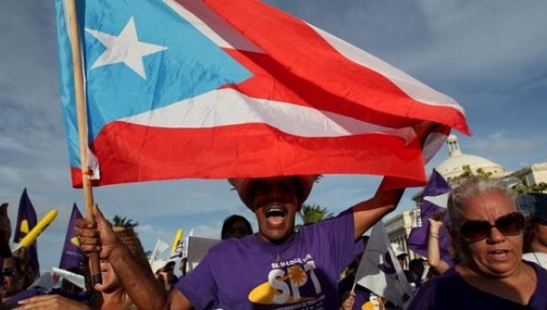 A member of a labor union shouts slogans while holding a Puerto Rico flag during a protest in San Juan Sept. 11 2015