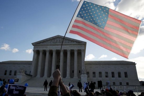 A person holds up the American flag in front of the U.S. Supreme Court in Washington March 2. CNS