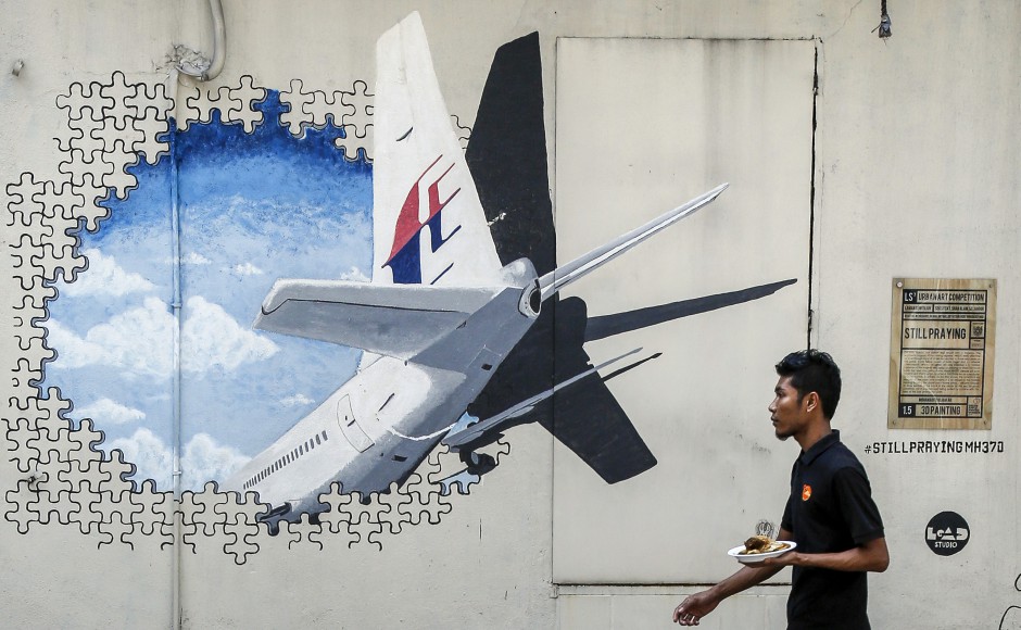 A waiter walks past a mural of flight MH370 in Shah Alam outside Kuala Lumpur Malaysia. Pic AP