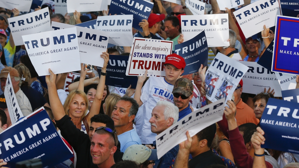 Audience members hold up signs supporting Republican presidential candidate Donald Trump during a campaign rally in Boca Raton Fla. on Sunday