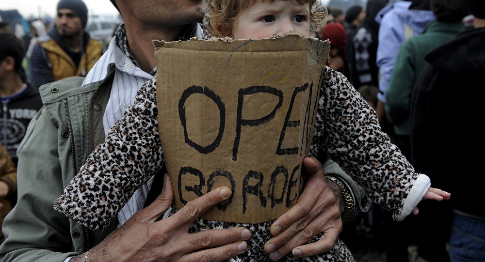 A stranded refugee holds a child during a protest at the Greek Macedonian border as they wait for the border crossing to reopen near the Greek village of Idomeni