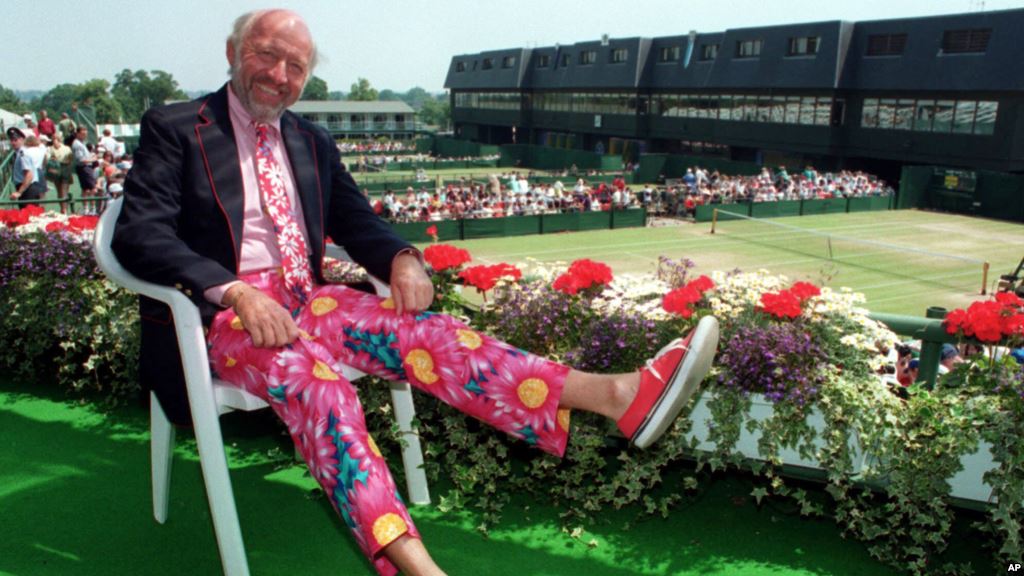 FILE- Tennis commentator Bud Collins known for his flashy attire displays a pair of brightly colored trousers as he sits overlooking the outside courts at Wimbledon England