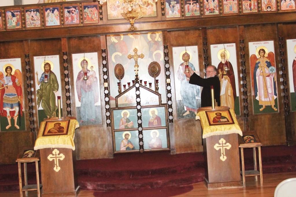 Father John Armstrong adjusts the candle on one of the icons at St. Herman Orthodox Church in Littleton. He explained the Orthodox Church uses a different calendar and will celebrate Easter on May 1