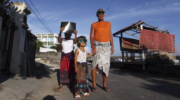 A family wear goggles to watch a solar eclipse in the sky during Nyepi the annual'Day of Silence during which Balinese Hindus welcome the New Year in Bali Indonesia Wednesday