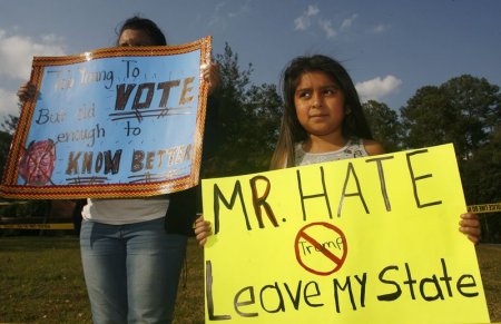 A young demonstrator holds up a sign protesting Republican presidential candidate Donald Trump down the street from a political campaign rally at the Valdosta State University Complex in Valdosta Georgia