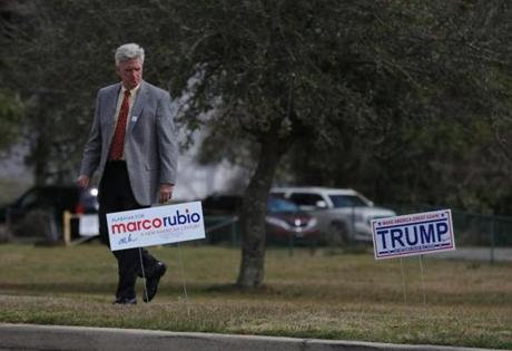 A man walks next to signs for Republican Presidential primary nominees Marco Rubio and Donald Trump outside a polling center in Mobile Alabama USA 01 March 2016. People in 12 states are voting in primary elections to determine the candidates for presid