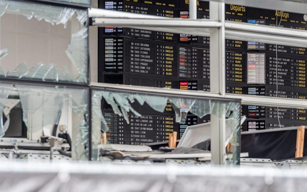 An arrivals and departure board is seen behind blown out windows at Zaventem Airport in Brussels on Wednesday