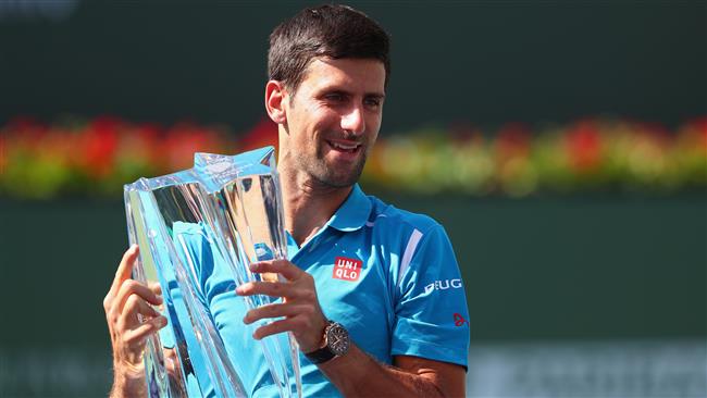 Novak Djokovic of Serbia holds up the winners trophy after his win over Milos Raonic of Canada during day fourteen of the BNP Paribas Open at Indian Wells Tennis Garden