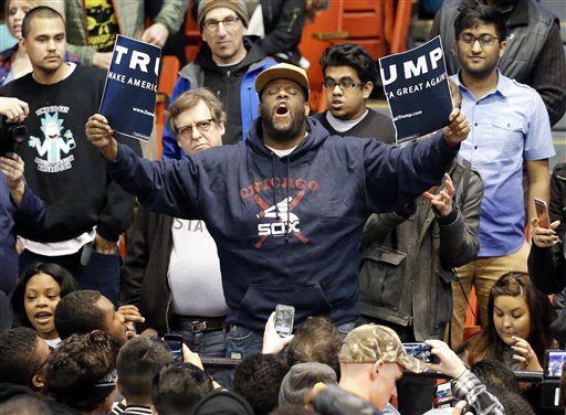 A protester holds up a ripped campaign sign for Republican presidential candidate Donald Trump before a rally on the campus of the University of Illinois-Chicago Friday