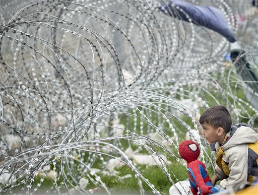 A boy plays with a Spiderman doll next to the razor wire around the fence between Greece and Macedonia at the northern Greek border station of Idomeni Monday