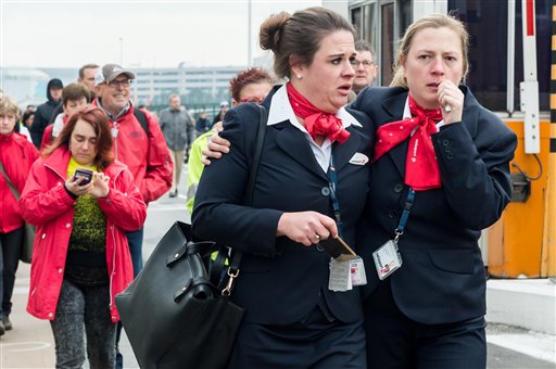 People react as they walk away from Brussels airport after explosions rocked the facility in Brussels Belgium Tuesday