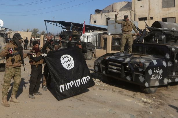 Members of Iraq's elite counter-terrorism service hold the Islamic State group's flag and flash the'V for victory sign