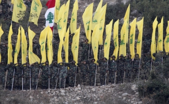 Members of Lebanon's Hezbollah wave Hezbollah and Lebanese flags during a rally marking the ninth anniversary of the end of Hezbollah's 2006 war with Israel in Wadi al-Hujeir southern Leban