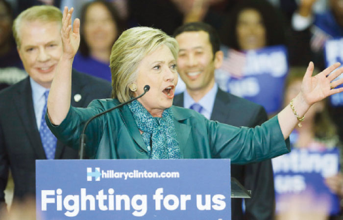 Democratic presidential candidate Hillary Clinton center speaks as Seattle Mayor Ed Murray left and his husband Michael Shiosaki right look on during a campaign rally at Rainier Beach High School in Seattle on Tuesday. — AP