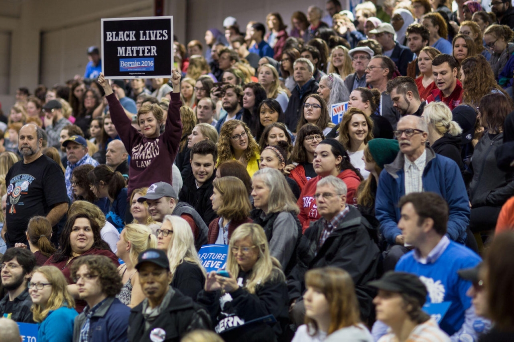 People wait for the arrival of Democratic presidential candidate Bernie Sanders at a campaign rally at Affton High School