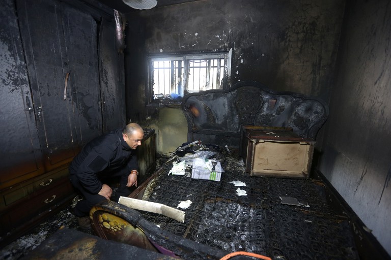 A Palestinian police member inspects the damage inside a burned-out house belonging to a key witness to an arson attack last year by Jewish extremists that killed a Palestinian family in the West Bank village of Duma after fire broke out in the home